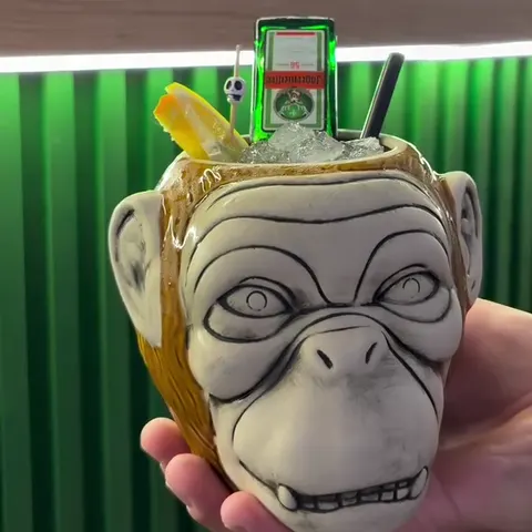 Коктелот Drunk Monkey во керамичка шолја во форма на мајмун, пред зелениот шанк
